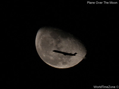 A plane flies in front of the Moon by worldtimezone